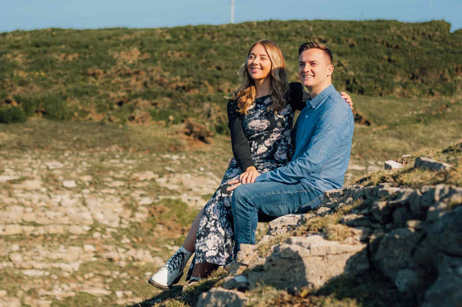 amy & Nath sat on a rock holding hands