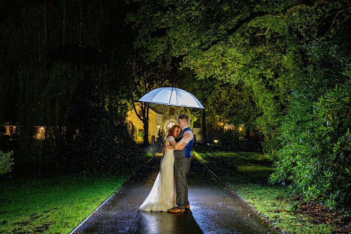 bride & groom cuddling in the rain